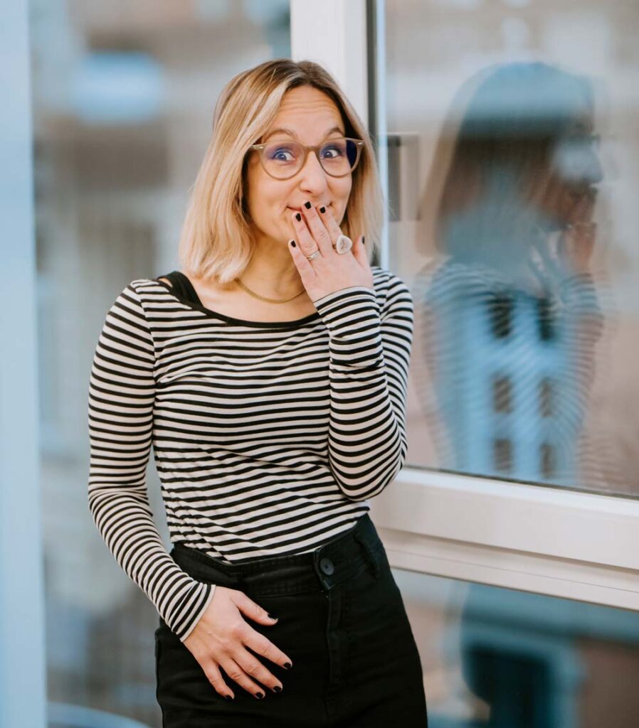 Carina Haferkamp, WordPress Berater, macht große, Augen, grinst und hält sich die Hand vor den Mund