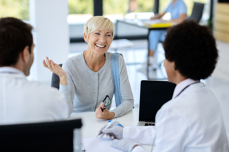 happy mature woman talking her doctor medical clinic